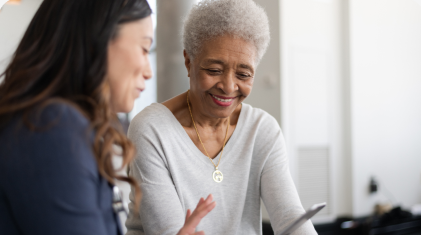 A grey haired Black woman talking to younger woman